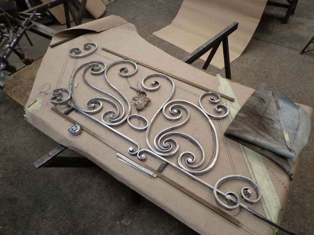 Volutes de ferronnerie en cours de composition sur une table de l’atelier.